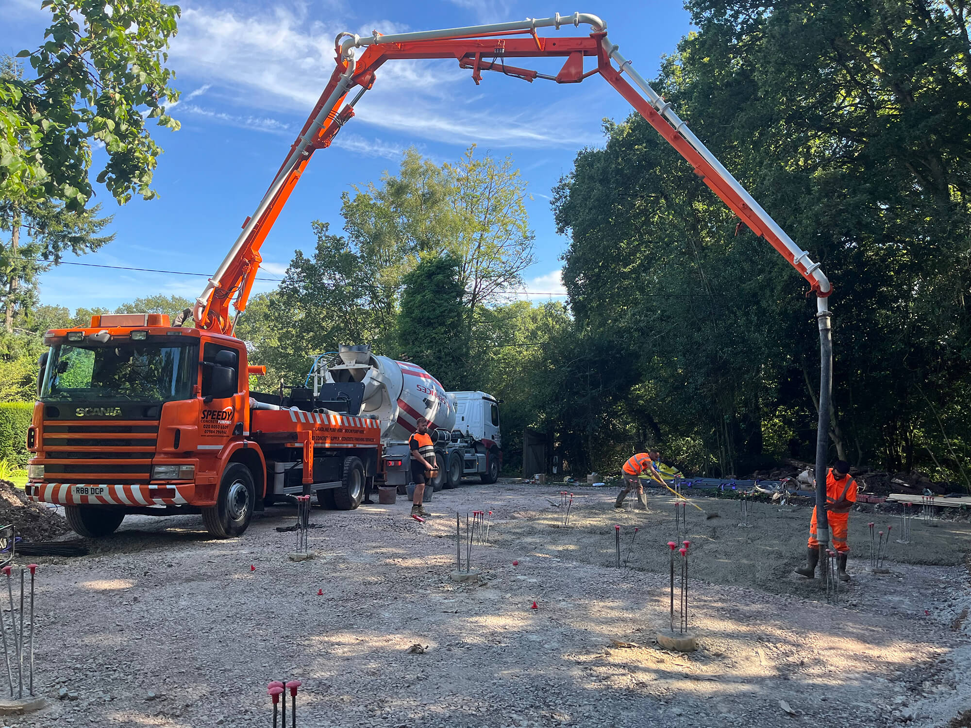 Orange Speedy Concrete Pumping boom pump with readymix truck on site